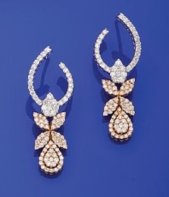 deux paires de boucles d'oreilles en diamant et en or posées sur un fond bleu