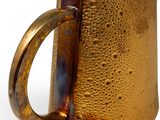 a gold pitcher with a handle on a white surface
