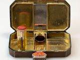 a small metal box with lipstick and other items in it