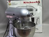 un robot de cuisine KitchenAid argenté, avec une boîte en arrière-plan