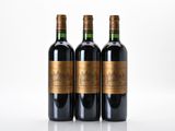 trois bouteilles de vin rouge sont posées côte à côte sur une surface blanche