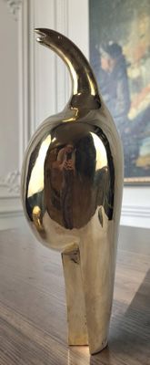 a silver vase sitting on a wooden table with a painting in the background