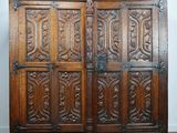 une armoire ancienne en chêne, avec des panneaux sculptés et des poignées en métal