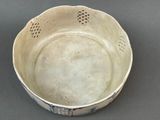 a white bowl that has holes in it on a table