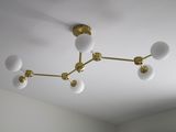a chandelier that has five white glass balls on it