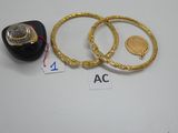 trois bagues en or et une bague avec une pièce de monnaie posées sur une table