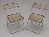 pair of chrome and glass folding chairs on a grey background