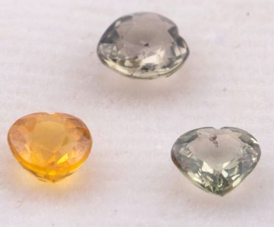 trois pierres précieuses de couleurs différentes posées sur une surface blanche