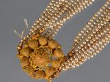 un gros plan sur un collier composé de perles et de perles en or
