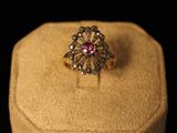 une image d'une bague en or avec une pierre rose au centre