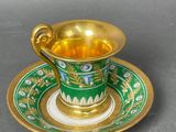 a green and gold cup and saucer sitting on a table