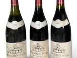 trois bouteilles de vin rouge sont alignées sur une surface blanche