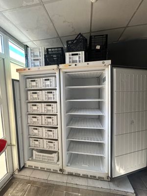 un réfrigérateur vide dans un coin de la pièce, avec des paniers posés dessus