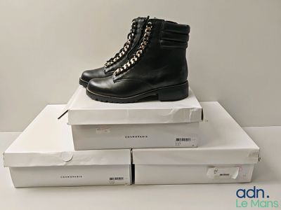 une paire de bottes noires posée sur une pile de cartons blancs