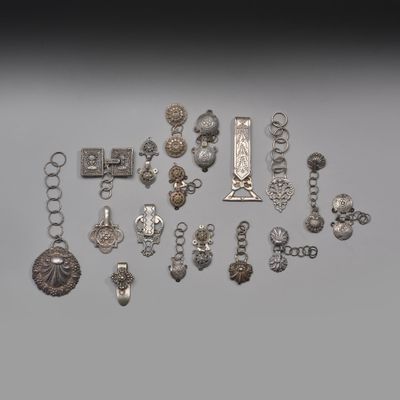 un assortiment d'objets en argent et de bijoux en argent présentés sur un fond gris
