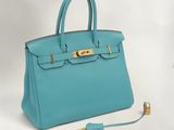 un sac à main en cuir bleu muni d'un fermoir doré sur la poignée