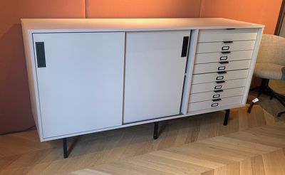 a white cabinet with drawers and a chair in front of it
