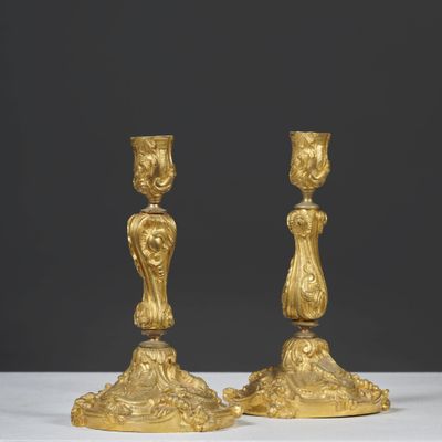 une paire de bougeoirs anciens en or posés sur une table blanche
