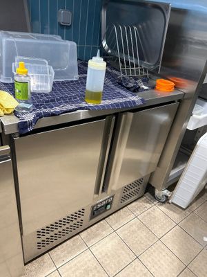 un plan de travail en acier inoxydable dans une cuisine au sol carrelé de bleu