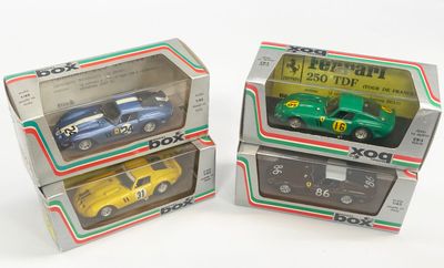 trois petites voitures dans leurs boîtes, posées sur une surface blanche