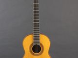 an acoustic guitar sitting on a stand against a gray background