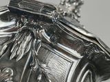 a silver vase with a bird on top of it