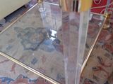 a glass coffee table with a gold base and a glass shelf