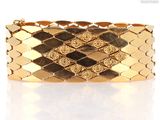 a close up of a gold bracelet on a white surface