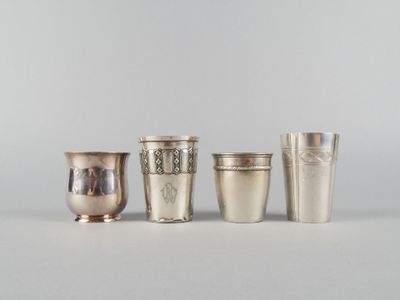 quatre tasses en argent sont alignées les unes à côté des autres sur une surface blanche