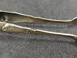 une paire de cuillères anciennes en argent posées sur un support gris