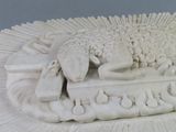 a white sculpture of a sheep laying on top of a table