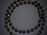 un collier en perles noires et dorées, muni d'un fermoir doré