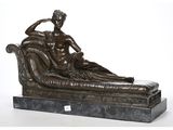 une statue en bronze représentant un homme assis sur un canapé