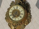 une horloge dorée posée sur un carreau blanc, sur une table