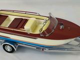 a small toy boat on a trailer on a white surface