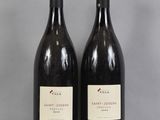 two bottles of wine sitting on top of a table next to each other