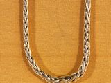 a close up of a silver necklace on a brown background