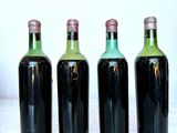 four bottles of wine are lined up on a marble surface