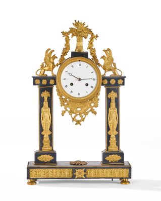 une horloge dorée et noire posée sur un socle orné de statues