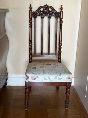 une chaise en bois dont l'assise est recouverte d'un tissu à motifs floraux, placée dans un coin de la pièce
