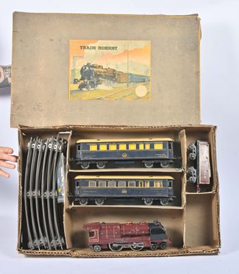 un circuit de train miniature dans une boîte en carton, avec une main qui tend vers lui