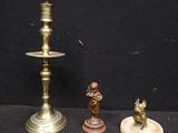 trois bougeoirs en laiton et une figurine sur fond noir