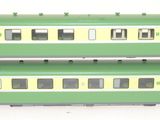 two green and yellow train cars sitting side by side
