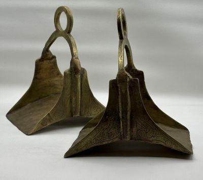 une paire de serre-livres anciens en laiton en forme de cloche, sur fond blanc