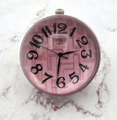 a pink clock sitting on top of a marble table