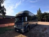 the mercedes bus is parked in a lot near a building