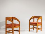 Deux chaises en bois avec des coussins rouges sont adossées à un mur blanc.