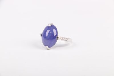 un gros plan d'une bague en pierre bleue posée sur une surface blanche