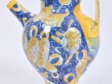 a blue and yellow vase sitting on a white surface