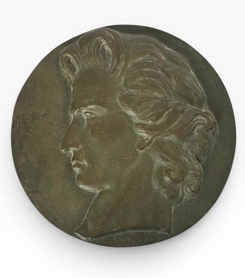 une vieille médaille en bronze sur laquelle est représenté le visage d'une femme